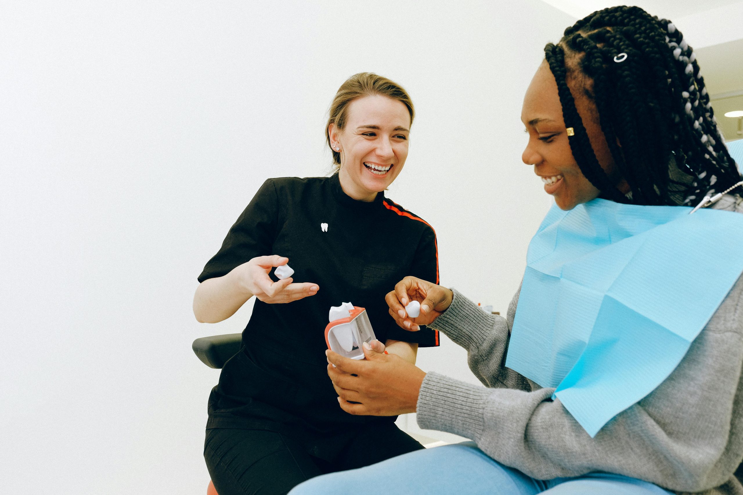  A smiling helpful dental assistant explains how to become a dental assistant and her salary while explaining tooth structures and dental hygiene to client. 